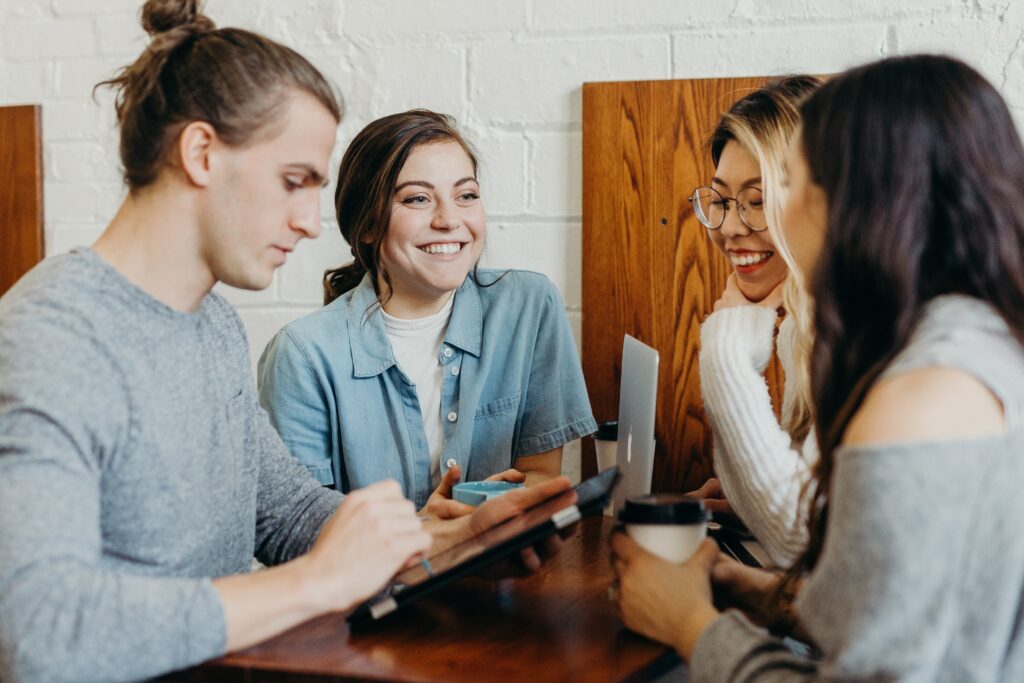 Four people share a moment of joy as they sit together around a table. The camaraderie is evident creating a warm and harmonious scene showing the effects of 5 Tips for Effective Communication.