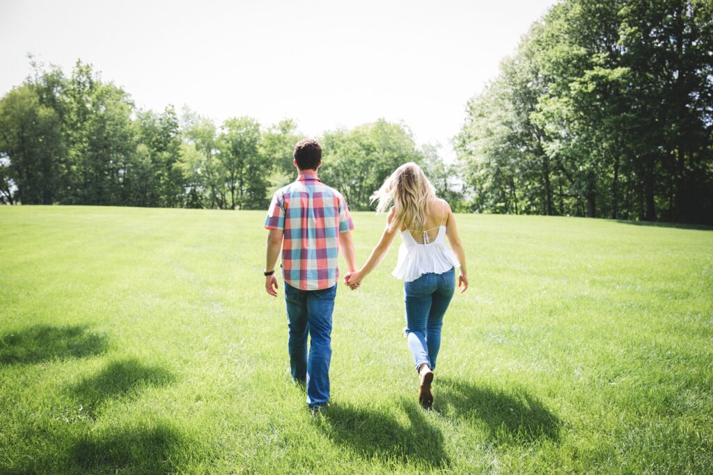 Image of couple holding hands walking in the grass where laughter and love turn into a celebration of togetherness when they learn about Taking a Break in Conversations
