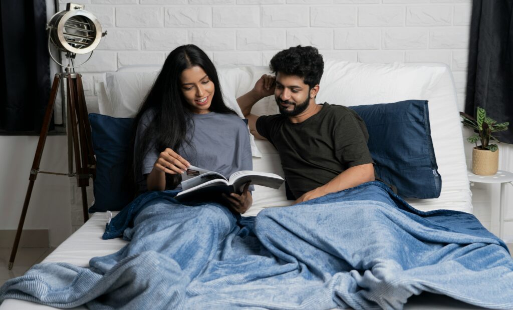 Image of a cozy couple shares tender moments of learning side by side in bed. Together, they explore the 5 Ways to Support Mental Health in Relationships